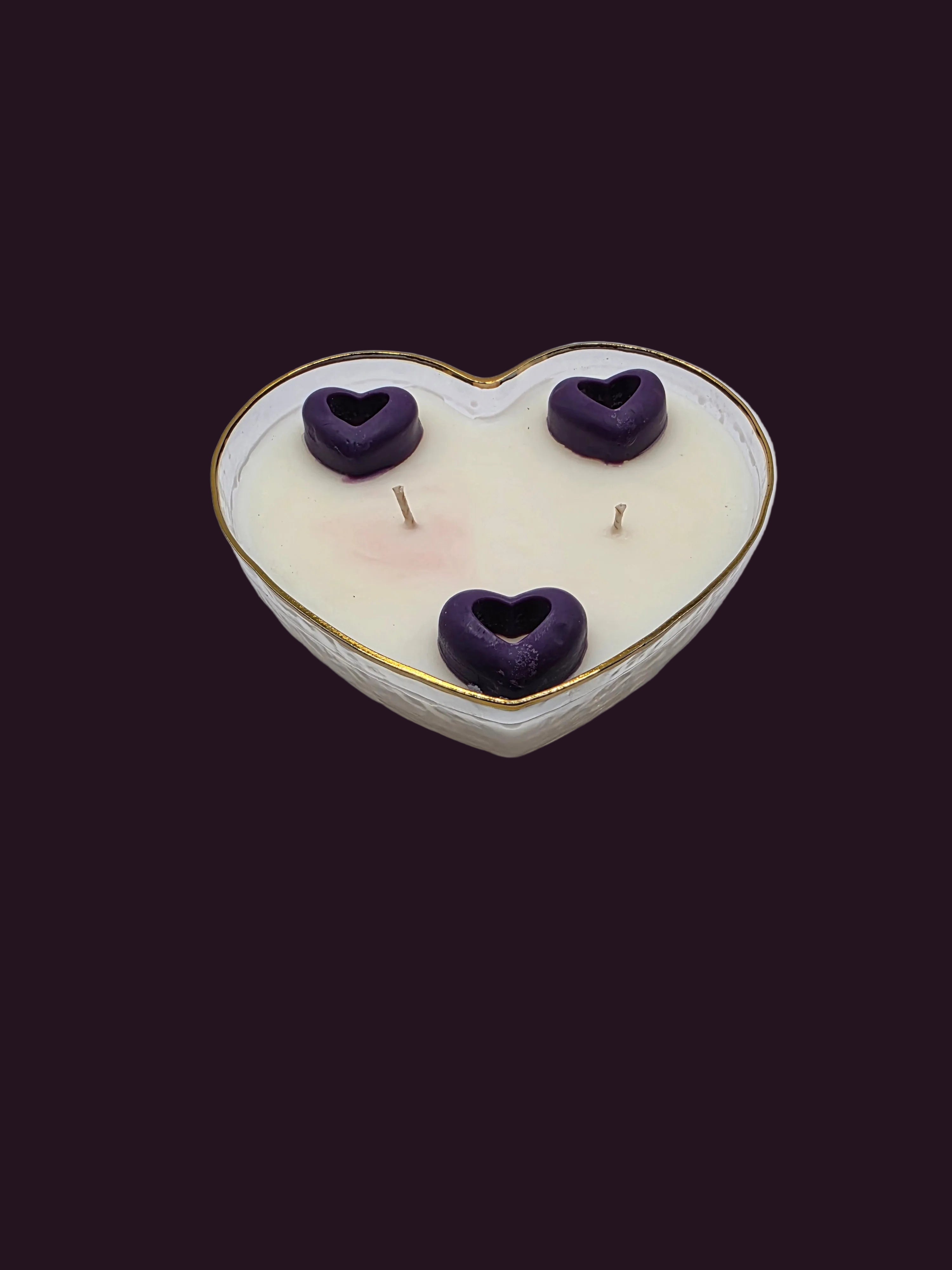 Heart-shaped candle with purple heart-shaped decorations on a white surface.